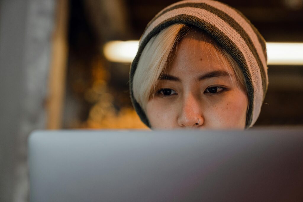 pexels-photo-4350285-4350285 Young woman with beanie concentrating on laptop in cozy café setting.