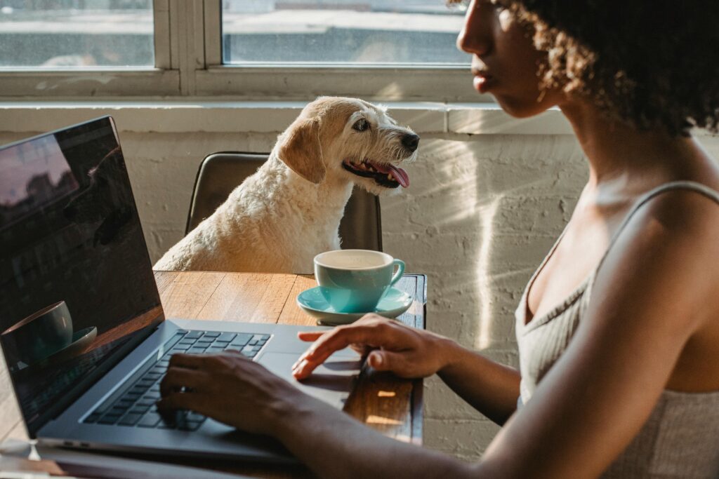 pexels-photo-5256147-5256147 A young woman works remotely at home, accompanied by her loyal dog and a cup of coffee.